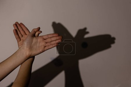 Foto de Manos de niño haciendo pájaro en la pared, sombras, juego con sombras en la pared - Imagen libre de derechos