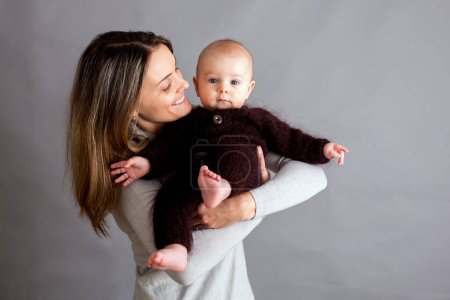 Photo for Young mother, caressing her newborn baby boy, holding him in her arms, different positions of holding baby, smiling from happiness - Royalty Free Image