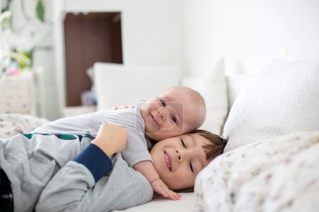 Photo for Two children, baby and his older brother in bed in the morning, playing together, laughing and having a good time, sharing special moment, bonding - Royalty Free Image