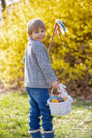 Foto de Cute preschool child, boy, holding handmade braided whip made from pussy willow, traditional symbol of Czech Easter used for whipping girls and women to receive eggs and sweets - Imagen libre de derechos