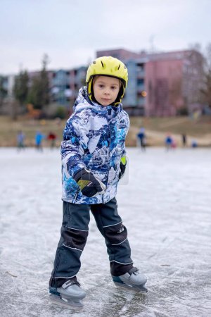 Foto de Niño feliz, niño, patinaje durante el día en el lago congelado, divertirse al aire libre - Imagen libre de derechos