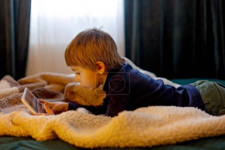 Téléchargez les photos : Enfant, écolier, jouer sur tablette à la maison, profiter d'un peu de temps libre - en image libre de droit