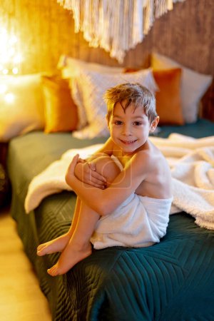 Photo for Cute child, boy, sitting at home in bed after shower in towel - Royalty Free Image