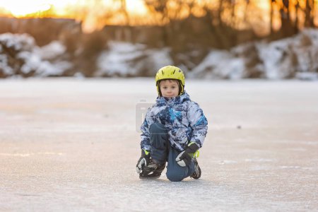 Téléchargez les photos : Joyeux enfant, garçon, patiner pendant la journée sur un lac gelé, s'amuser à l'extérieur - en image libre de droit