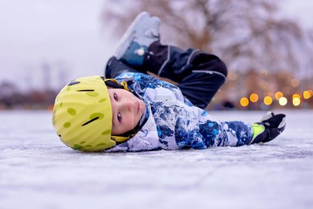 Téléchargez les photos : Joyeux enfant, garçon, patiner pendant la journée sur un lac gelé, s'amuser à l'extérieur - en image libre de droit