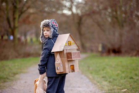 Photo for Little child, blond boy with pet dog, carying home on his back, kid, having paper house, emotional shot - Royalty Free Image
