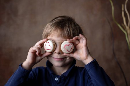 Photo for Beautiful blond child, boy, holding box with sweet macaroons for valentine - Royalty Free Image