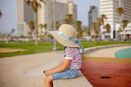 Photo for Cute child with straw hat, enjoying the seaside views in Tel Aviv on a hot summer day, afternoon - Royalty Free Image