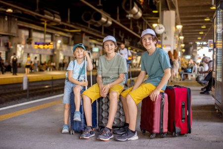 Photo for Children, boy brothers holding suitcases, travelin, waiting at trainstation to go to the airport for a family holiday - Royalty Free Image