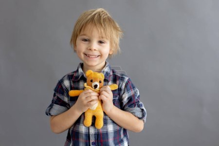 Foto de Niño pequeño, niño rubio, jugando con pequeño juguete de punto hecho a mano - Imagen libre de derechos