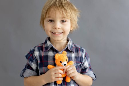 Foto de Niño pequeño, niño rubio, jugando con pequeño juguete de punto hecho a mano - Imagen libre de derechos
