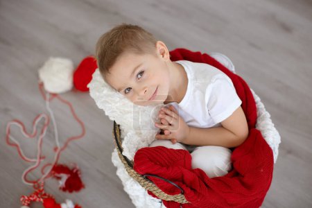 Enfant mignon, garçon blond, jouant avec bracelet blanc et rouge, martenitsa bulgare