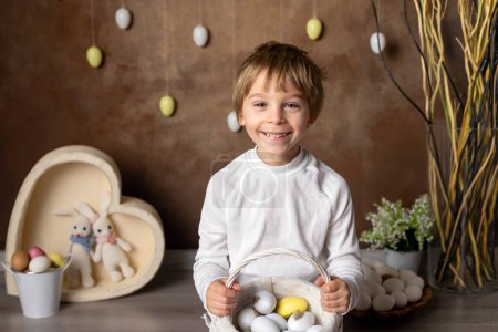 Téléchargez les photos : Mignon écolier, garçon, panier avec des œufs de Pâques sur fond de Pâques, plan de studio - en image libre de droit