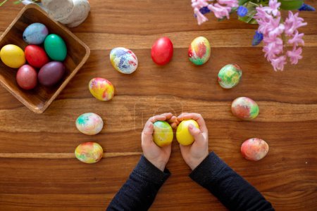 Pequeño niño rubio niño para colorear huevos de Pascua en casa, República Checa tradición con ramitas y huevos