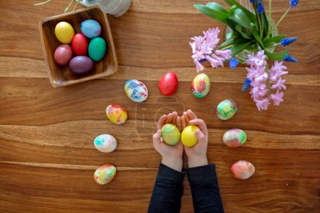 Pequeño niño rubio niño para colorear huevos de Pascua en casa, República Checa tradición con ramitas y huevos