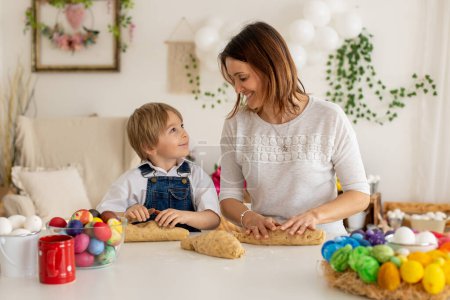 Photo for Little blond toddler child with young mother, preparing dough for easter brioche buns, sweet easter bread with nuts and dry fruits - Royalty Free Image