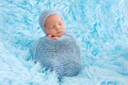 Téléchargez les photos : Bébé garçon mignon, dormant paisiblement enveloppé dans un emballage bleu sur une fourrure bleue, dans un sac de pommes de terre - en image libre de droit