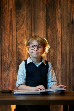 Téléchargez les photos : Enfant mignon, garçon portant des lunettes, lisant un livre à la maison, plan studio - en image libre de droit