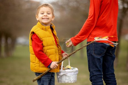 Foto de Cute preschool child, whipping his sister on Easter with twig, braided whip made from pussy willow, traditional symbol of Czech Easter used for whipping girls and women - Imagen libre de derechos