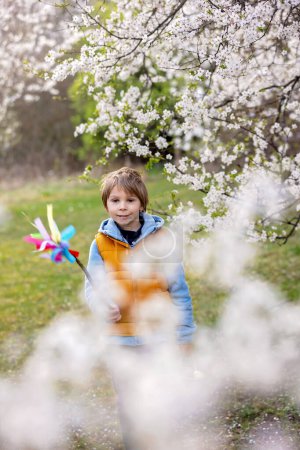 Foto de Beautiful blond child, boy, holding twig, braided whip made from pussy willow, traditional symbol of Czech Easter used for whipping girls and basket with eggs in park - Imagen libre de derechos