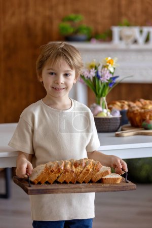 Photo for Cute preschool child, boy, holding sweet brioche bun for Easter, traditional swee bread baked with almonds, nuts and sugar, home - Royalty Free Image