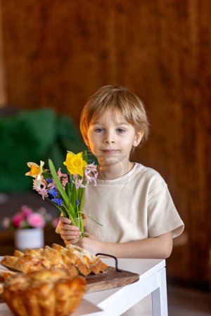 Photo for Cute preschool child, boy, holding sweet brioche bun for Easter, traditional swee bread baked with almonds, nuts and sugar, home - Royalty Free Image
