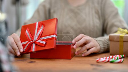 Foto de Una mujer abre una hermosa caja de regalo de Navidad en su mesa. Navidad o Año Nuevo concepto de vacaciones. imagen recortada - Imagen libre de derechos