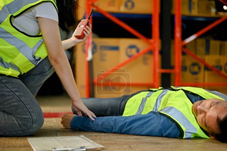Photo for An unconscious Asian warehouse male worker receives first aid from a female colleague in the warehouse. pass put, faint, blackout, dead while working. - Royalty Free Image