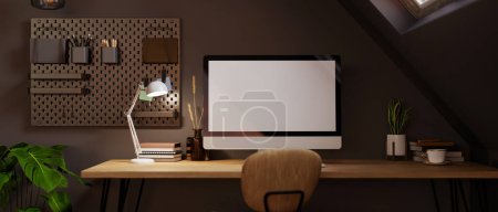 Téléchargez les photos : Espace de travail moderne à la maison sombre dans la conception intérieure de la pièce grenier avec maquette d'ordinateur de bureau PC, lumière de la lampe de table et accessoires sur table en bois, pegboard sur mur noir. 3d rendu, illustration 3d - en image libre de droit