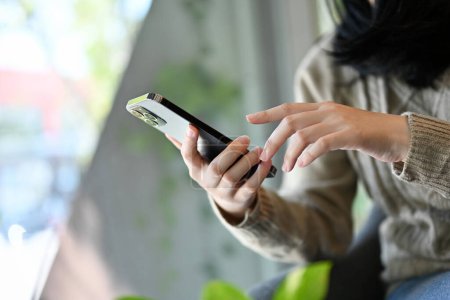 Photo for Close-up, side view. A young Asian female using her smartphone, touching on mobile screen. texting, messaging, reading online news, sending email - Royalty Free Image