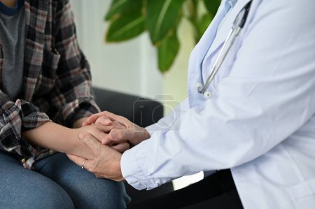 cropped image, A professional female doctor holding a patient's hands, giving support and reassuring