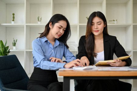 Photo for Attractive Asian female accountants working together in the office, working on their sales and financial report. - Royalty Free Image