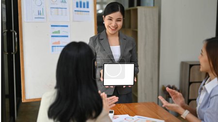 Photo for A professional and successful millennial Asian businesswoman or business consultant leads the meeting, training her employees and presenting something on a tablet screen. tablet white screen mockup - Royalty Free Image