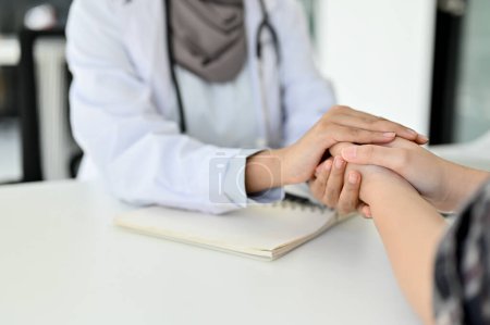 Foto de Imagen de primer plano, Un médico tranquiliza a un paciente sosteniendo suavemente las manos del paciente mientras consulta el plan de cirugía. - Imagen libre de derechos