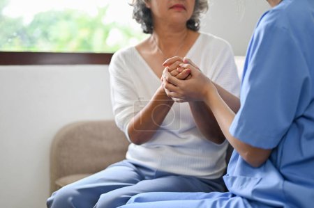 Foto de Una doctora sosteniendo las manos de una paciente anciana, dando apoyo y consuelo durante la reunión. imagen recortada y de primer plano - Imagen libre de derechos