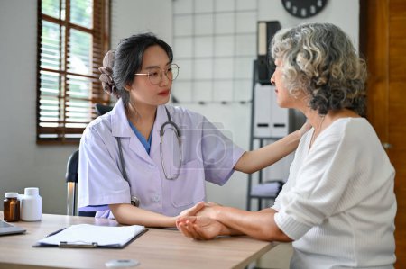 Photo for A caring millennial Asian female doctor holds a patient's hand to comfort and reassure the patient during the medical checkup. health care concept - Royalty Free Image