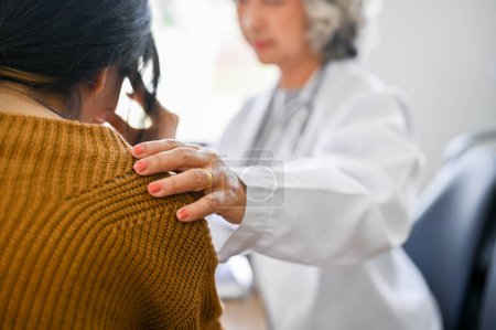 Photo for Professional Asian female doctor touching shoulder to comfort and support her patient. A young Asian female patient is being reassured by her doctor. close-up image - Royalty Free Image
