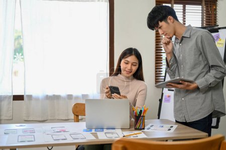 Téléchargez les photos : Des développeurs professionnels asiatiques, hommes et femmes, sont dans la salle de réunion pour travailler ensemble sur leur nouveau prototype d'application mobile. UI UX concept de démarrage d'entreprise - en image libre de droit