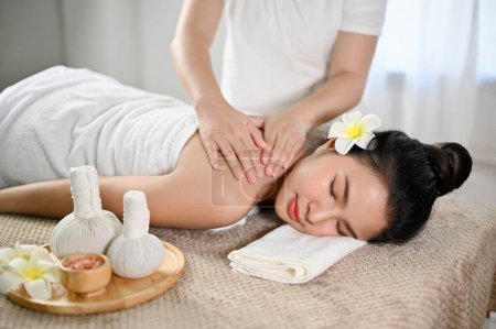 Téléchargez les photos : Belle et détendue jeune asiatique femme recevoir massage, couché sur la table de massage dans le salon de spa thaïlandais. Aromathérapie, Thérapeutique, Bien-être - en image libre de droit