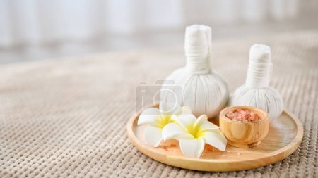 Photo for Spa herbal balls, Himalayan salt and frangipani flowers on a wooden tray on massage table. close-up image, Spa, massage, Thai spa concept - Royalty Free Image