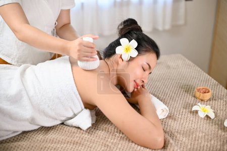 Photo for Top view, Beautiful and attractive Asian woman lying on massage table, receiving body massage with a spa herbal ball in Thai spa salon. Traditional Thai massage concept - Royalty Free Image