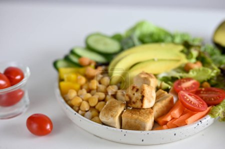 Téléchargez les photos : Close-up image, Healthy salad mixed with grilled tofu. chickpea, tomatoes, avocado, cucumber, green salad vegetables. Vegan food and plant based recipe concept - en image libre de droit