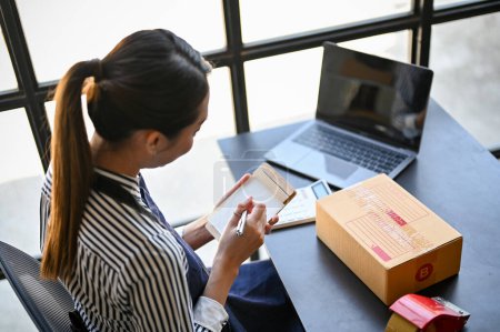 Téléchargez les photos : Beautiful and attractive millennial Asian businesswoman working at her desk in her home office, listing her online orders. top view - en image libre de droit