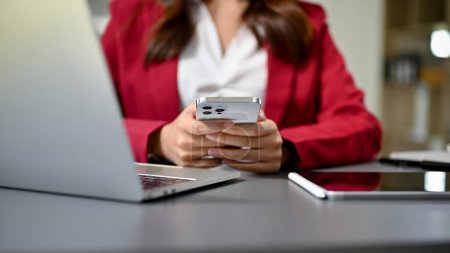 Photo for Beautiful businesswoman or female boss using her smartphone at her desk, texting or sending email, checking meeting schedule, searching information on the internet. cropped image - Royalty Free Image