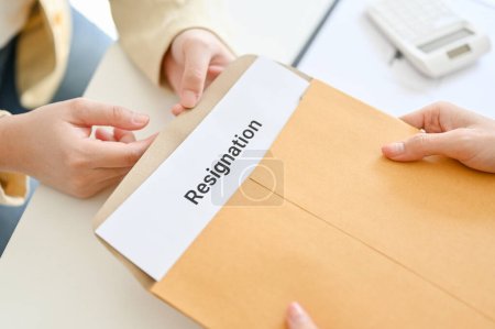 Photo for An office employee sending a resignation letter to her manager. Change of job, unemployment, quit a job. close-up top view image - Royalty Free Image