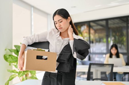 Foto de Sad young Asian female office worker carrying her personal stuff in the office. being fired, resigning from a company or changing jobs. - Imagen libre de derechos