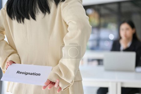 Photo for Close-up image of a female office worker hiding a resignation letter behind her back while talking with her annoying boss in the office. leaving job, resignation - Royalty Free Image