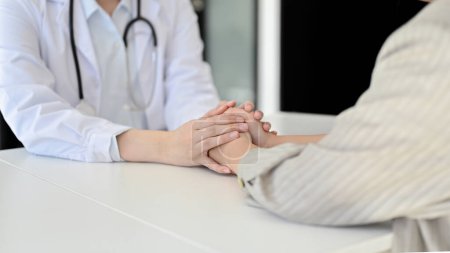 Photo for Close-up image of a caring female doctor holding a patient's hands to reassure and comfort her before discussing the surgery and treatment plan. - Royalty Free Image