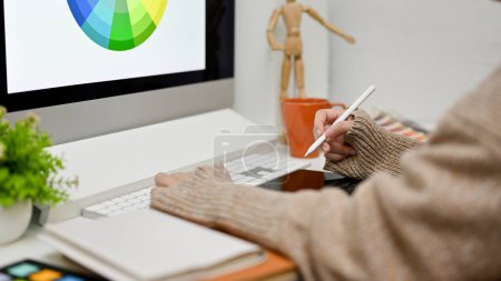 Foto de Vista lateral de una diseñadora gráfica femenina que trabaja en su escritorio, usando computadora y tableta gráfica, diseñando un nuevo prototipo de sitio web. - Imagen libre de derechos