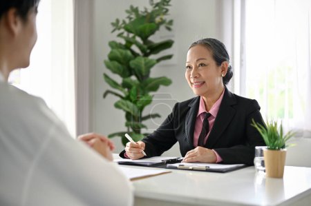 Atractiva mujer de negocios asiática senior se centra en escuchar las respuestas de un candidato y, satisfecho con las respuestas. Concepto de entrevista laboral